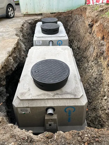 La micro-station en béton posée au fond de la fouille, deux tampons ronds sur le dessus.